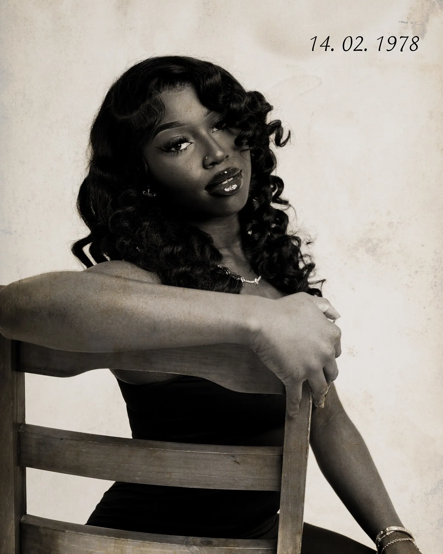 Sepia portrait of a woman with curled hair leaning on the back of a wooden chair, dated 14. 02. 1978 in the corner