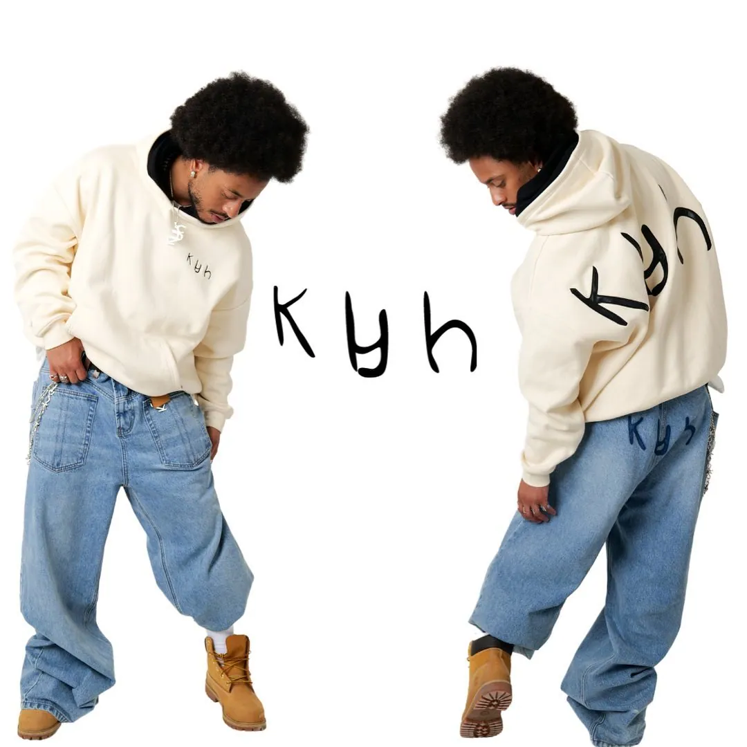 Two views of a man in a cream hoodie, baggy jeans and tan boots, front and back, with the Klyh logo on the white backdrop
