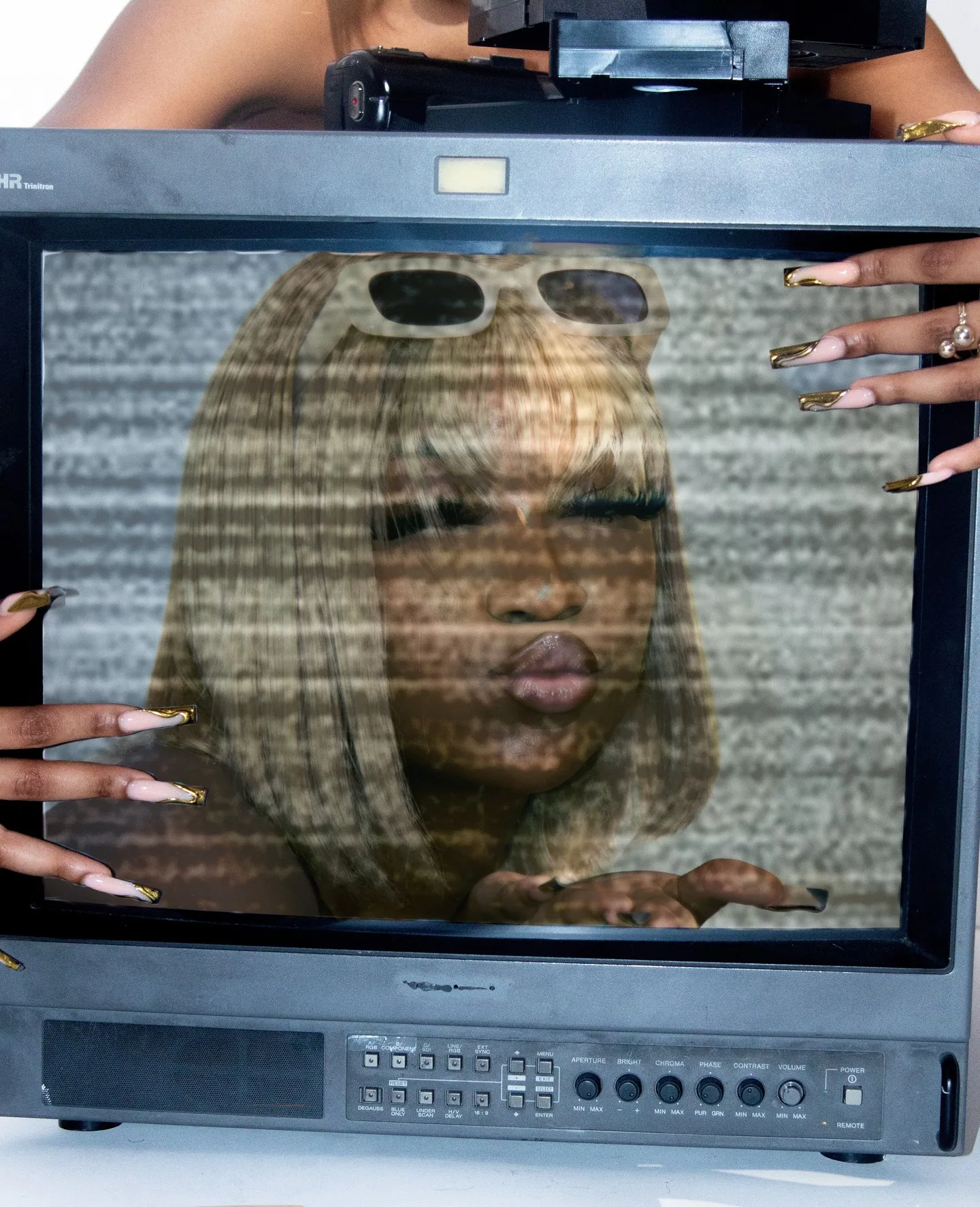 Old television screen with a static-streaked image of a blonde woman blowing a kiss, hands framing the set